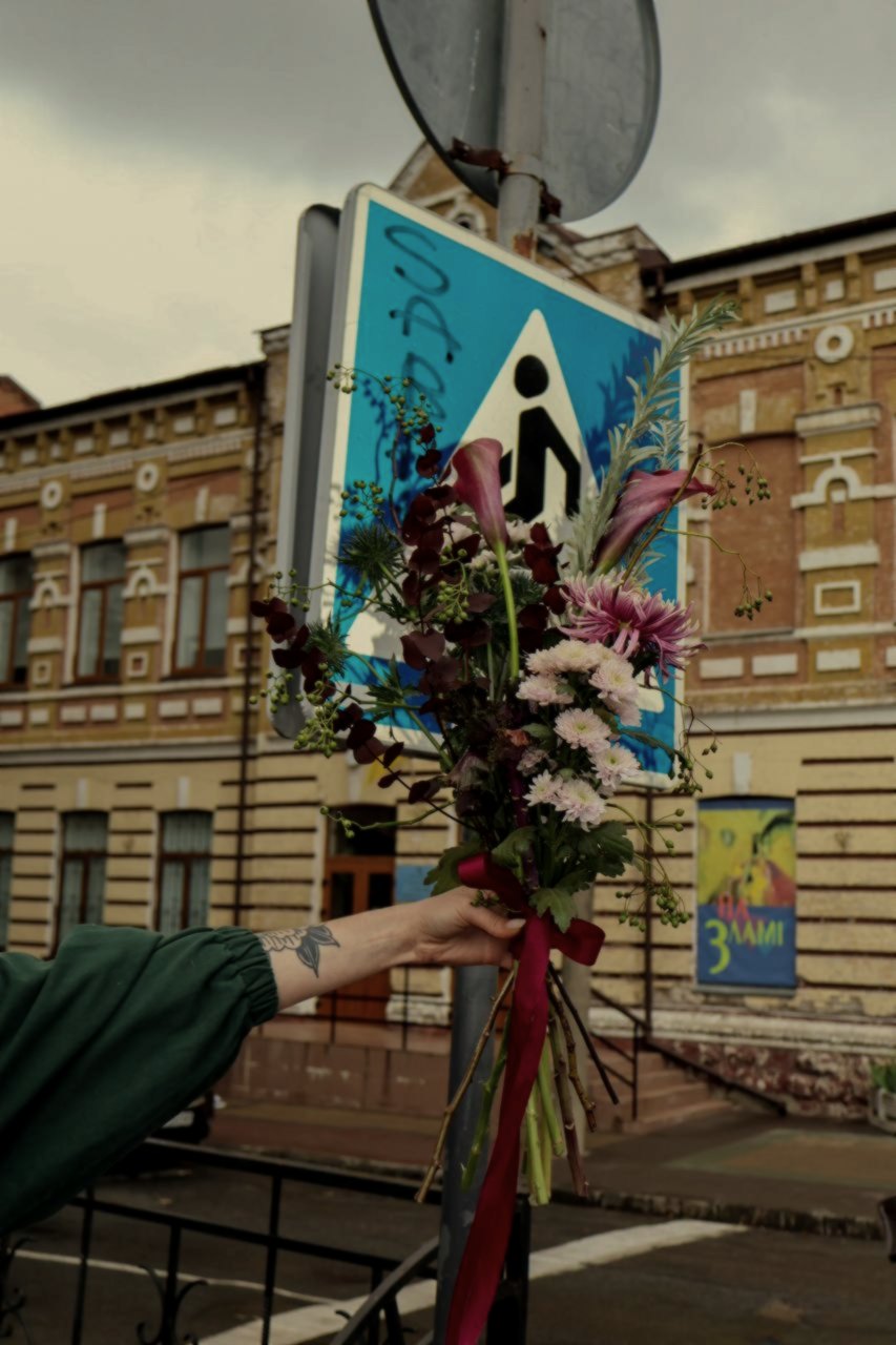 A bouquet held beside a street sign